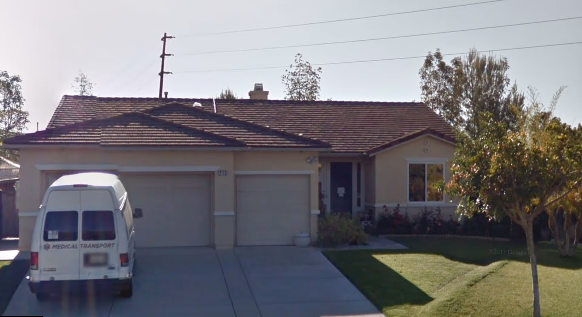Front view of a single-story retirement home with a three-car garage and parked van.