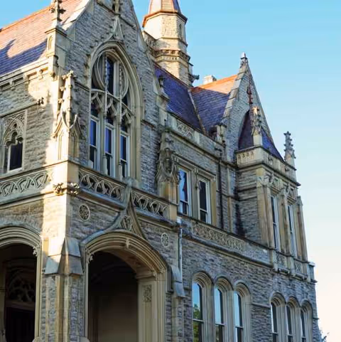 Stone Gothic-style building with arched windows and intricate carvings against a blue sky