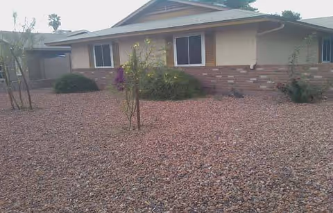 Front view of a single-story assisted living home with a gravel desert yard.
