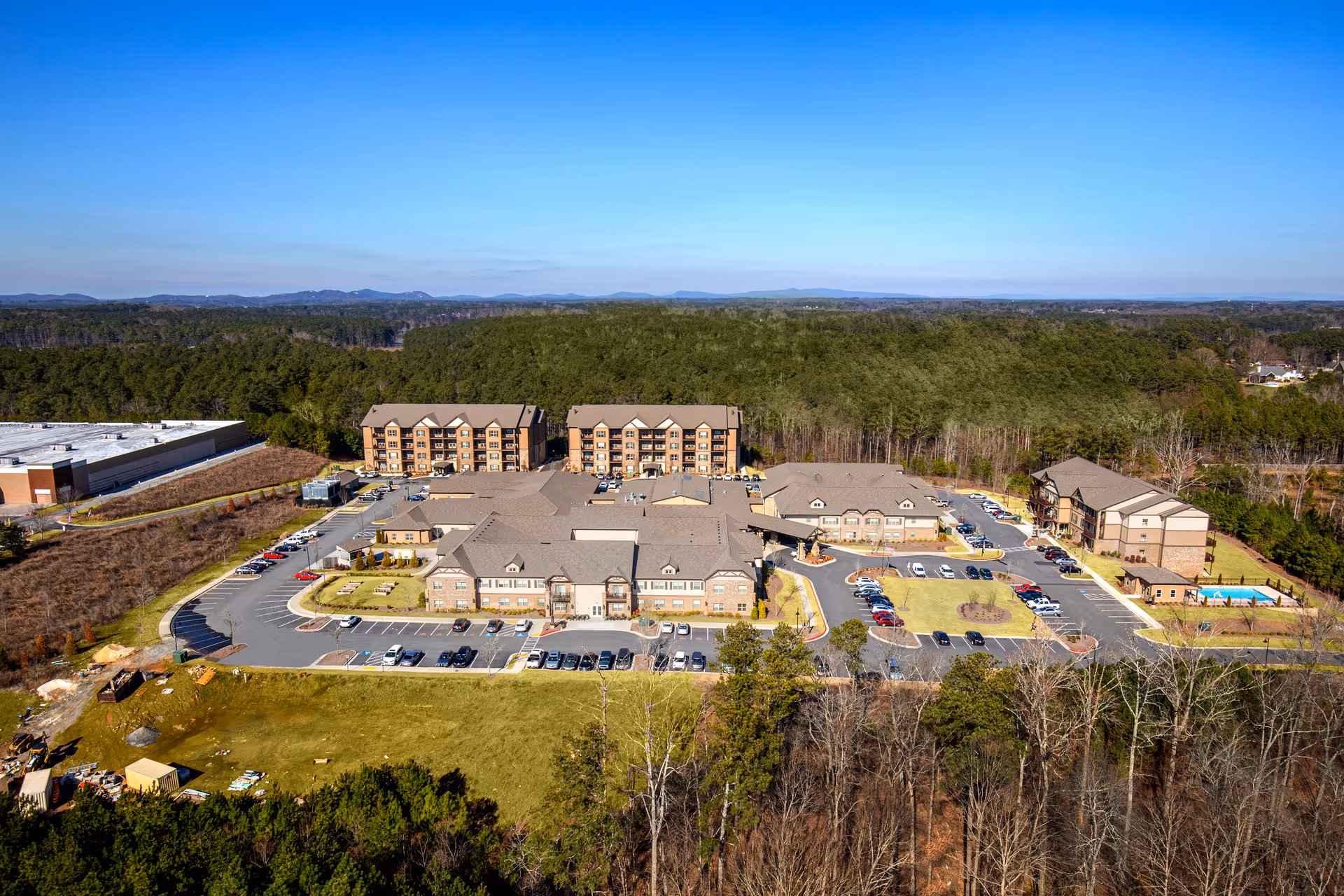 Aerial view of Celebration Village Acworth campus showing multiple brick residential buildings, parking lots, pool area, and surrounding trees.