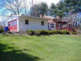 White, single-story building with red doors and green lawn in front, shrubs.