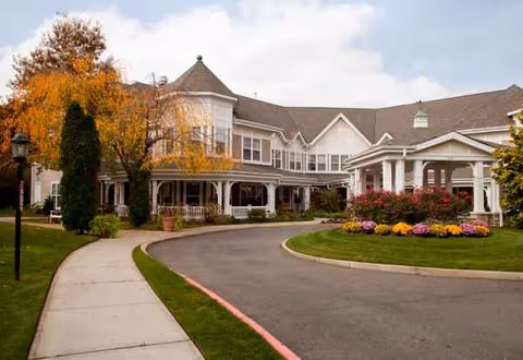 Exterior view of Sunrise of North Lynbrook with curved driveway and landscaped entrance.