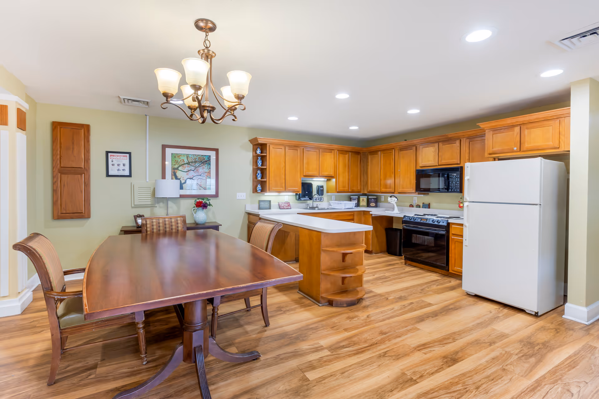 Open dining area and kitchen with a wooden dining table, chandelier, center island, wood cabinets, and a white refrigerator.