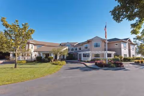 Wide view of Ivy Park at Oakland Hills exterior building with flag, parking lot, and landscaping.