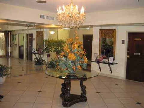 Westchester Villa lobby with chandelier, glass table, and potted plants.