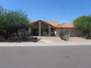 Single-story building with a tile roof and desert landscaping along a street.