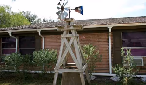 Single-story brick facility with a wooden windmill ornament in a small landscaped yard.