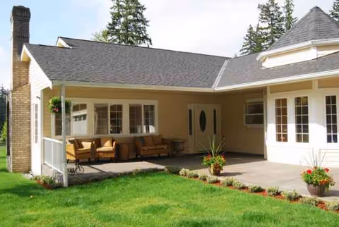 Beige, single-story senior care facility exterior with a covered porch and outdoor seating.