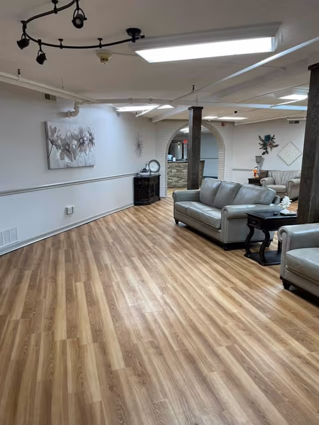 Spacious common room with wood-look flooring, multiple sofas, side tables, and decorative wall art.