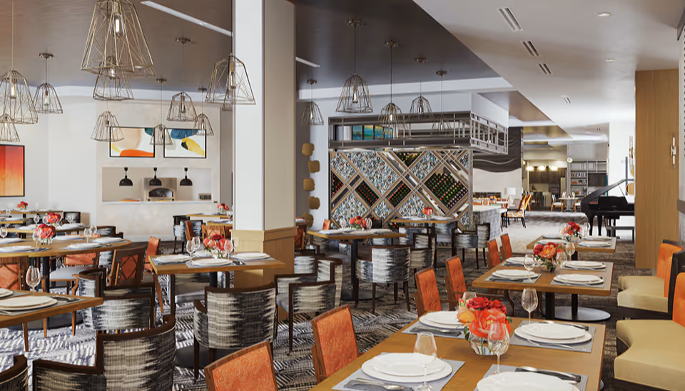 Spacious, well-lit dining room with multiple set tables, pendant lights, floral centerpieces, and a piano in the background.