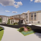 Exterior view of a multi-story senior living facility with a covered entrance, stone and siding facade, landscaped greenery, and a driveway with a white car parked near the entrance.