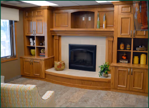 Living room with large wooden built-in cabinets surrounding a central fireplace and a patterned upholstered chair.