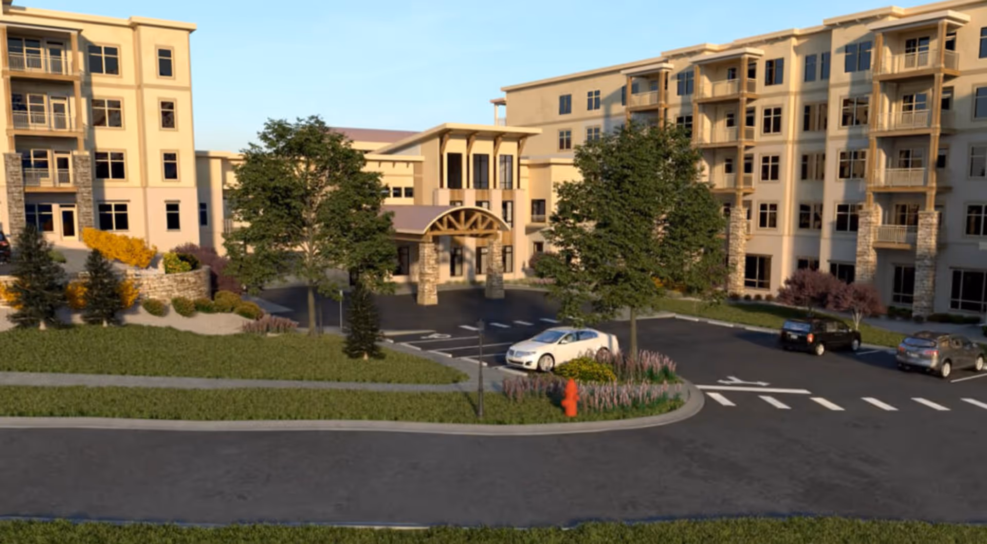 Exterior view of Aberdeen Ridge senior living facility showing a large multi-story building with balconies, a covered entrance supported by stone pillars, landscaped greenery, trees, a parking lot with several cars, and a fire hydrant near the sidewalk.