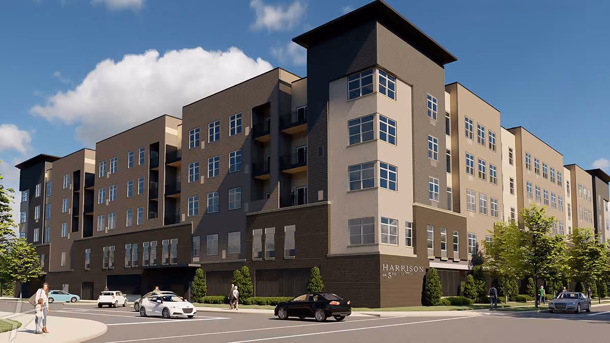 Exterior view of the multi-story Harrison on 5th senior living building on a city street with cars and pedestrians.