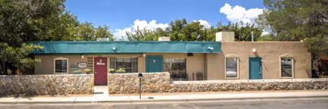 Front view of a single-story building with turquoise awning and stone facade.