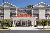 Conifer Village at Cambridge exterior: two-story building with a red-roofed entrance.