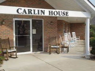 Brick facility entrance with glass doors and outdoor chairs in front of Carlin House.