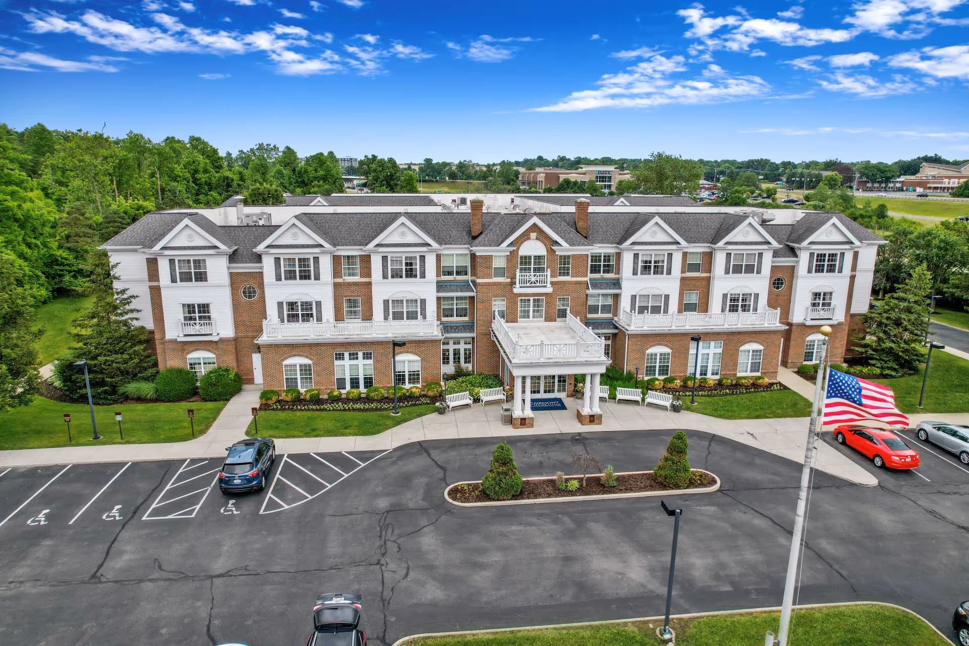 Aerial view of a brick senior living facility with entrance canopy and parking.