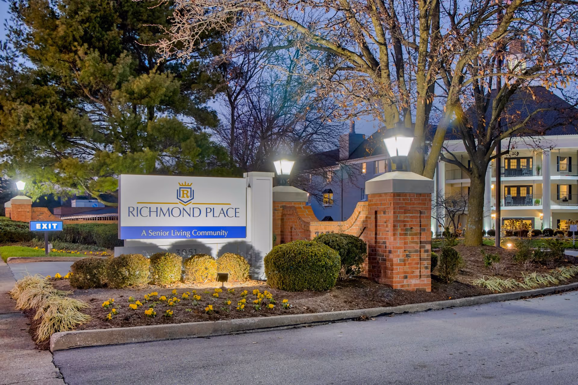Illuminated entrance sign and front facade of Richmond Place senior living community at dusk.