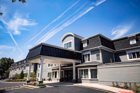 Exterior view of Arbor Terrace Shrewsbury senior living facility with covered entrance and parking.