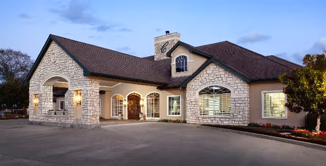 Stone-faced senior living facility with arched entrance and large front windows.
