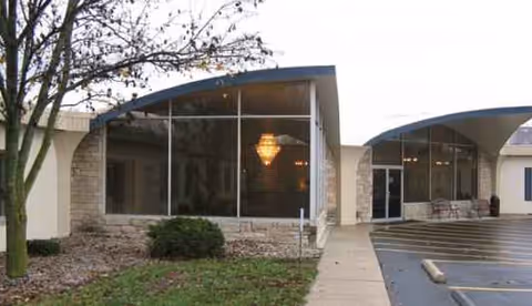 Front exterior view of Miller's Merry Manor with glass doors and curved canopies.