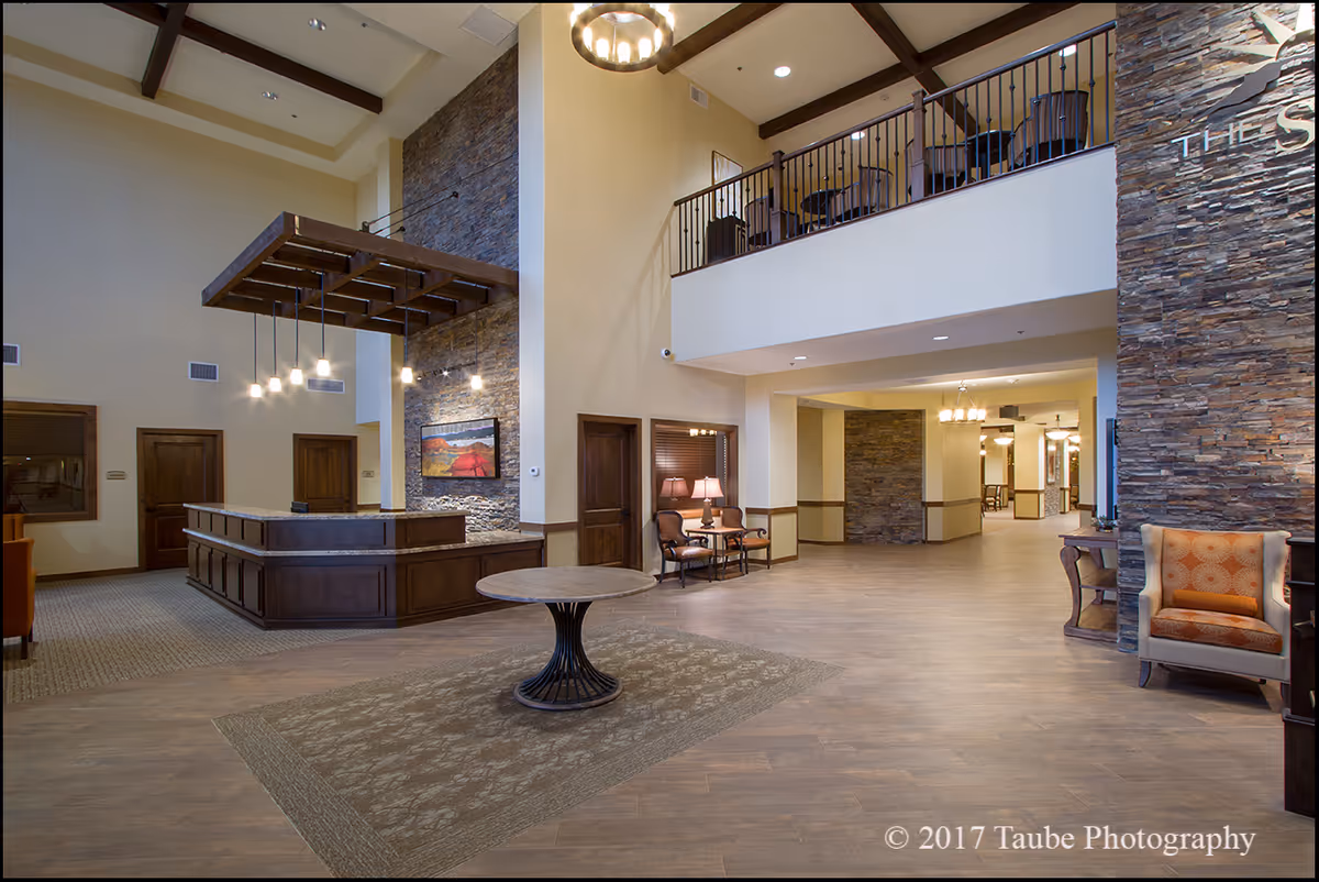 Spacious two-story reception lobby with a front desk, seating areas, and stone accent walls.