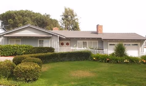 Single-story care facility with manicured lawn and trimmed hedges in front.