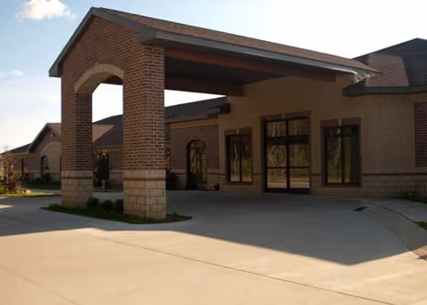 Front entrance of a brick building with a covered porte-cochere and glass doors.