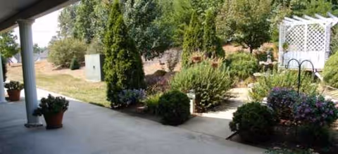 Outdoor covered walkway with a garden, potted plants, and a white lattice trellis.