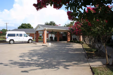 Exterior view of Alvarado Meadows nursing facility entrance with a parked white van.