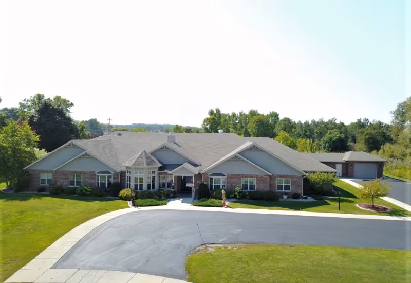 Front exterior of a single-story assisted living building with brick facade and green landscaping.