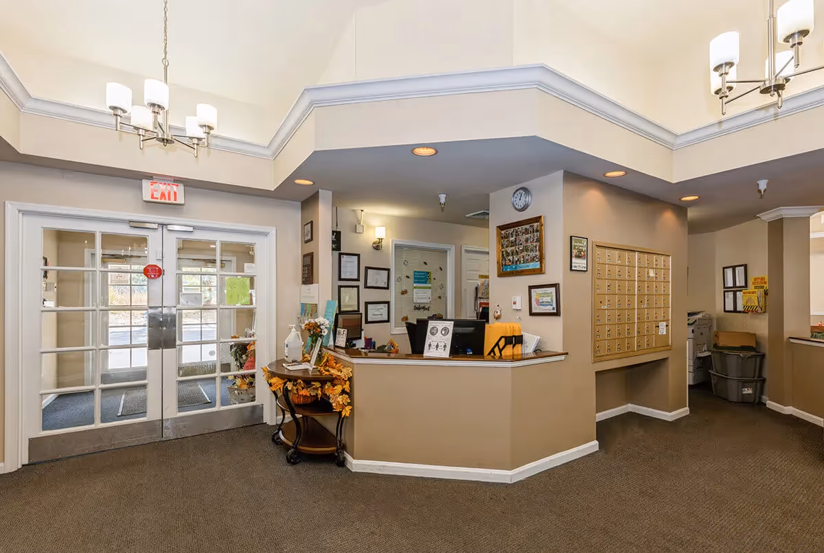 Reception lobby with glass double doors, a check-in desk, and a wall of mailboxes.