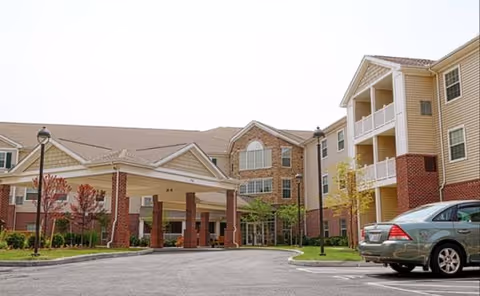 Exterior view of a Danbury senior living facility with a covered entrance and parked car.