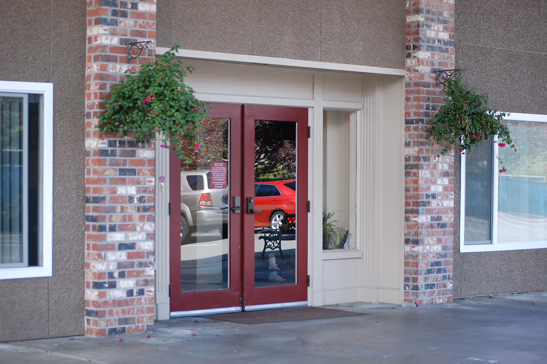Entrance of Everett Plaza with double red glass doors flanked by brick columns and hanging flower baskets.
