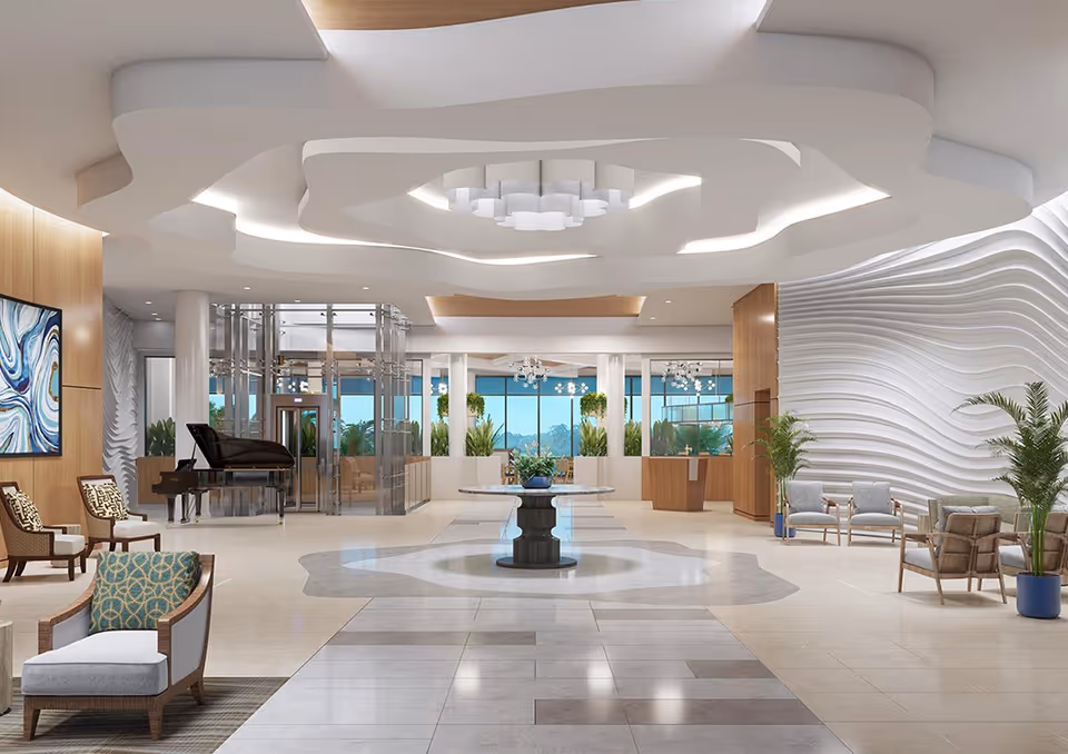 Spacious and modern senior living facility lobby with a decorative ceiling, a round table with a plant centerpiece in the middle, comfortable seating areas with chairs and sofas, a grand piano, large windows with views of greenery outside, and textured white wall panels.