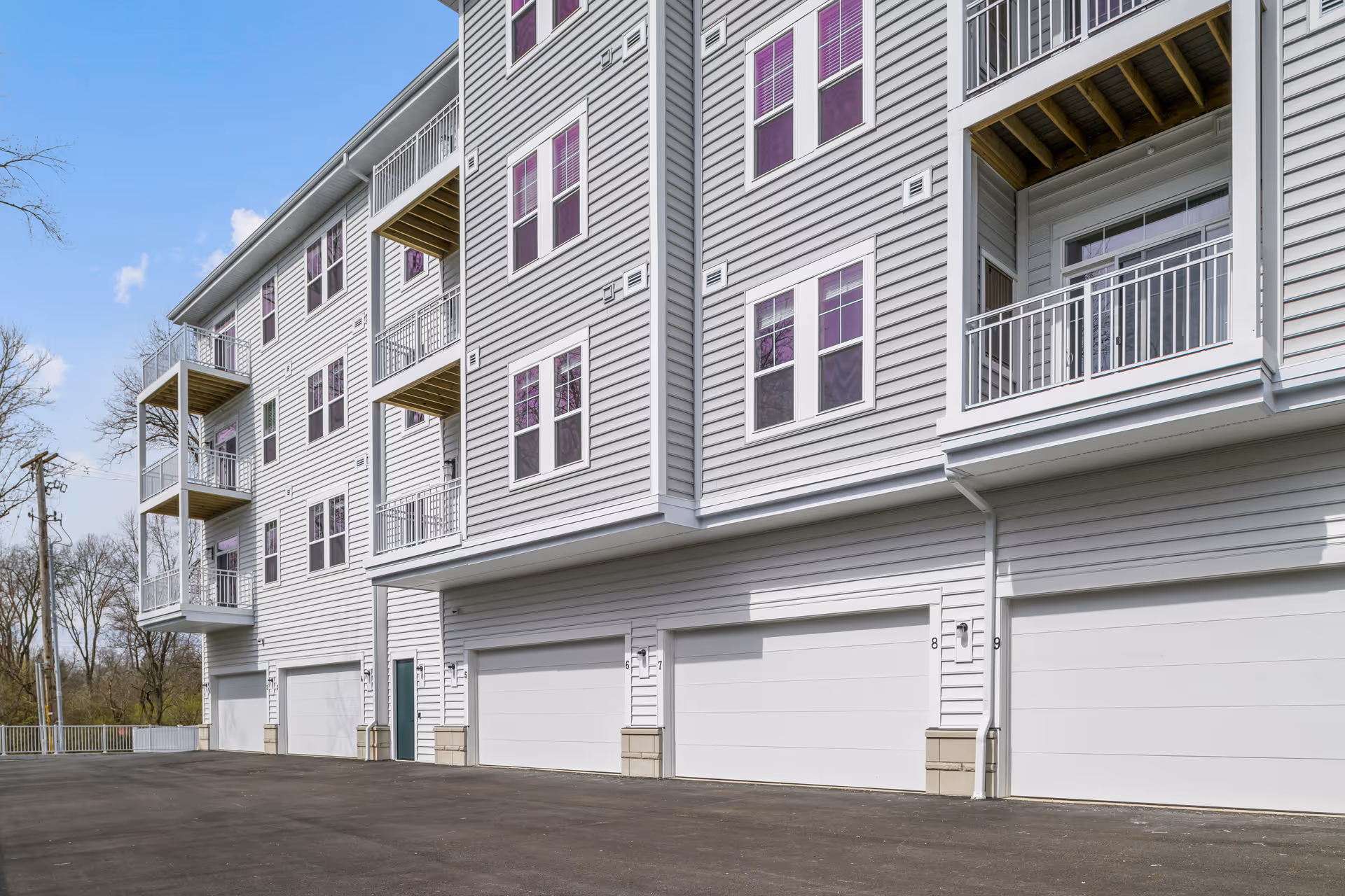 Exterior view of a multi-story residential building with balconies and ground-level garage doors.