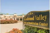 Exterior view of Candlewood Valley Health and Rehabilitation Center with a large sign displaying the facility's name in the foreground and the building in the background under a clear blue sky.