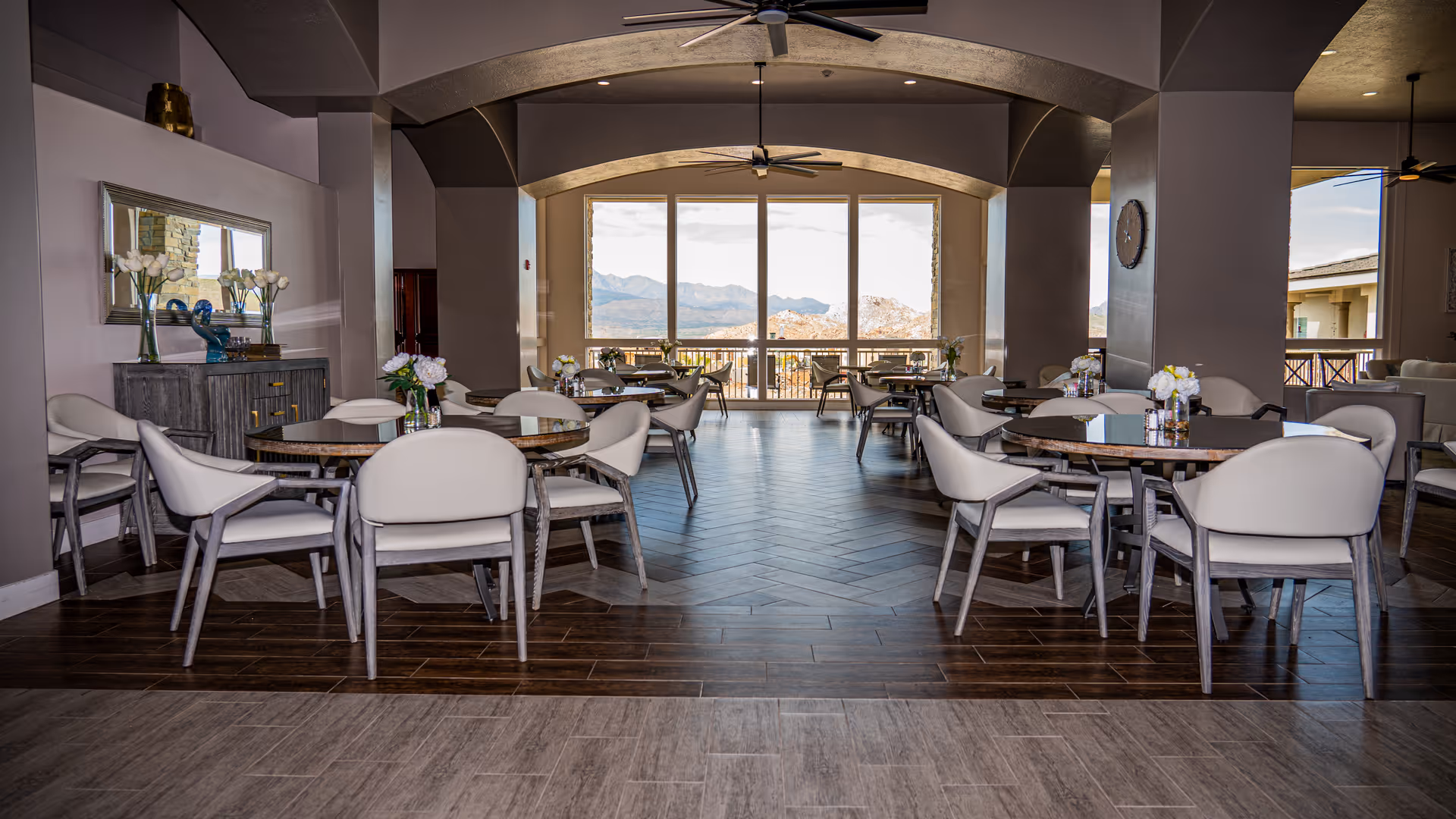 Spacious dining room with round tables and modern chairs facing large windows that reveal mountain views.
