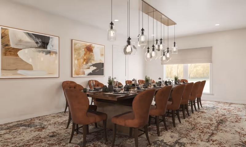 A spacious dining room with a long wooden table surrounded by twelve brown upholstered chairs. The table is set with plates, glasses, and decorative plants. Above the table hang multiple modern pendant lights with clear glass shades. The room has light-colored walls adorned with two abstract paintings and a large window with a beige roman shade letting in natural light. The floor is covered with a patterned carpet in neutral tones.