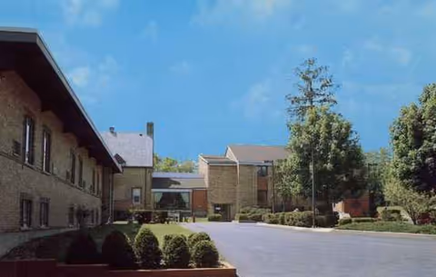 Exterior view of a retirement home with parking and trees.