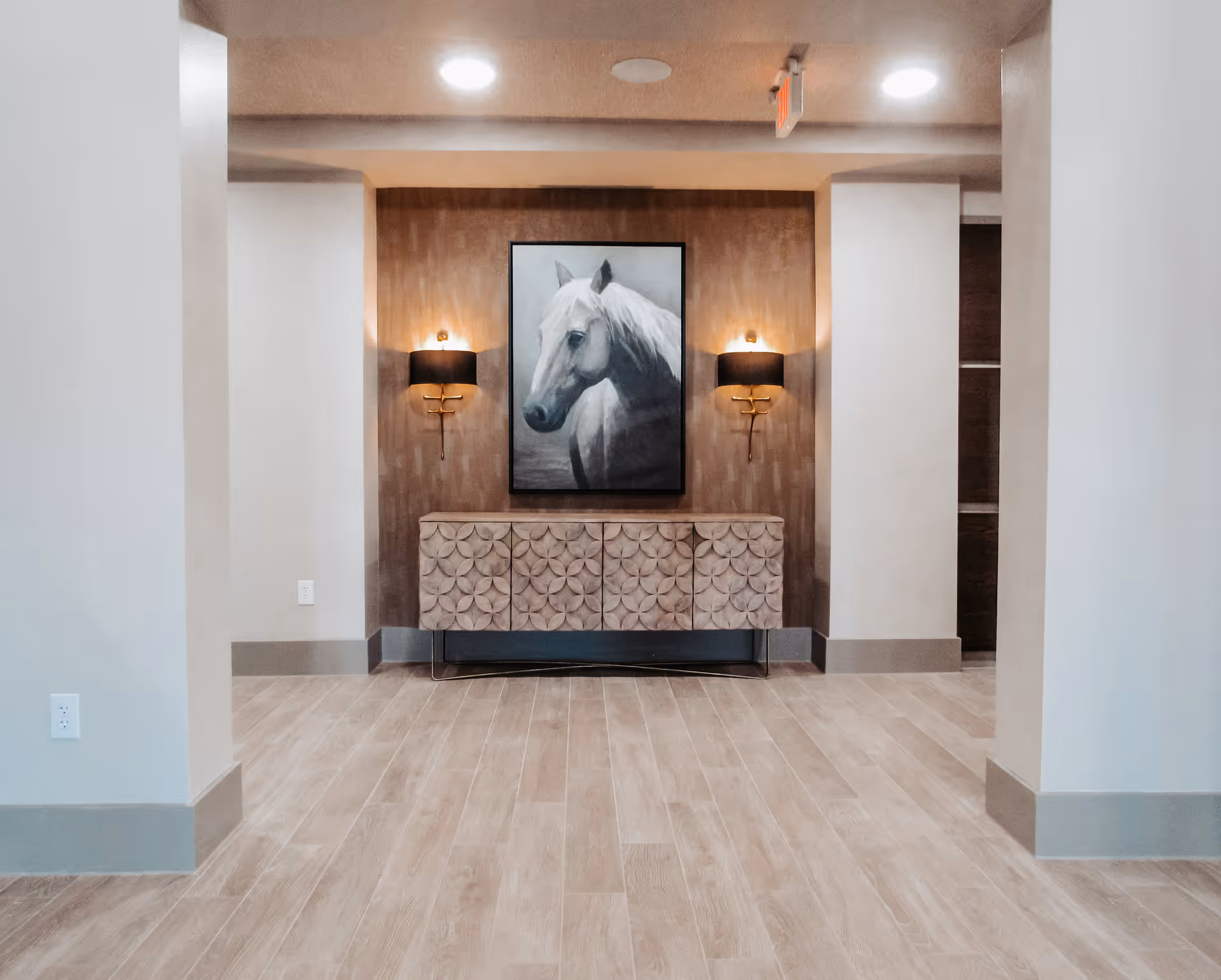 Modern interior foyer with a decorative console, a large horse portrait, and two wall sconces.