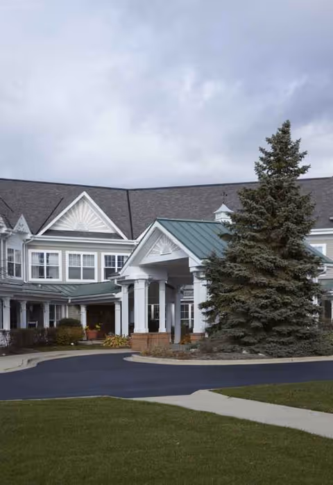 Exterior view of The Glenn Buffalo facility with peaked roof, entrance, and evergreen tree.