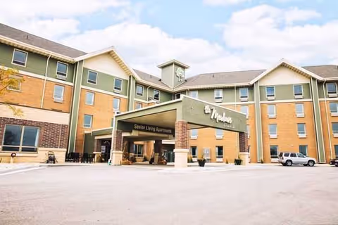 Exterior view of a senior living facility with a covered entrance.