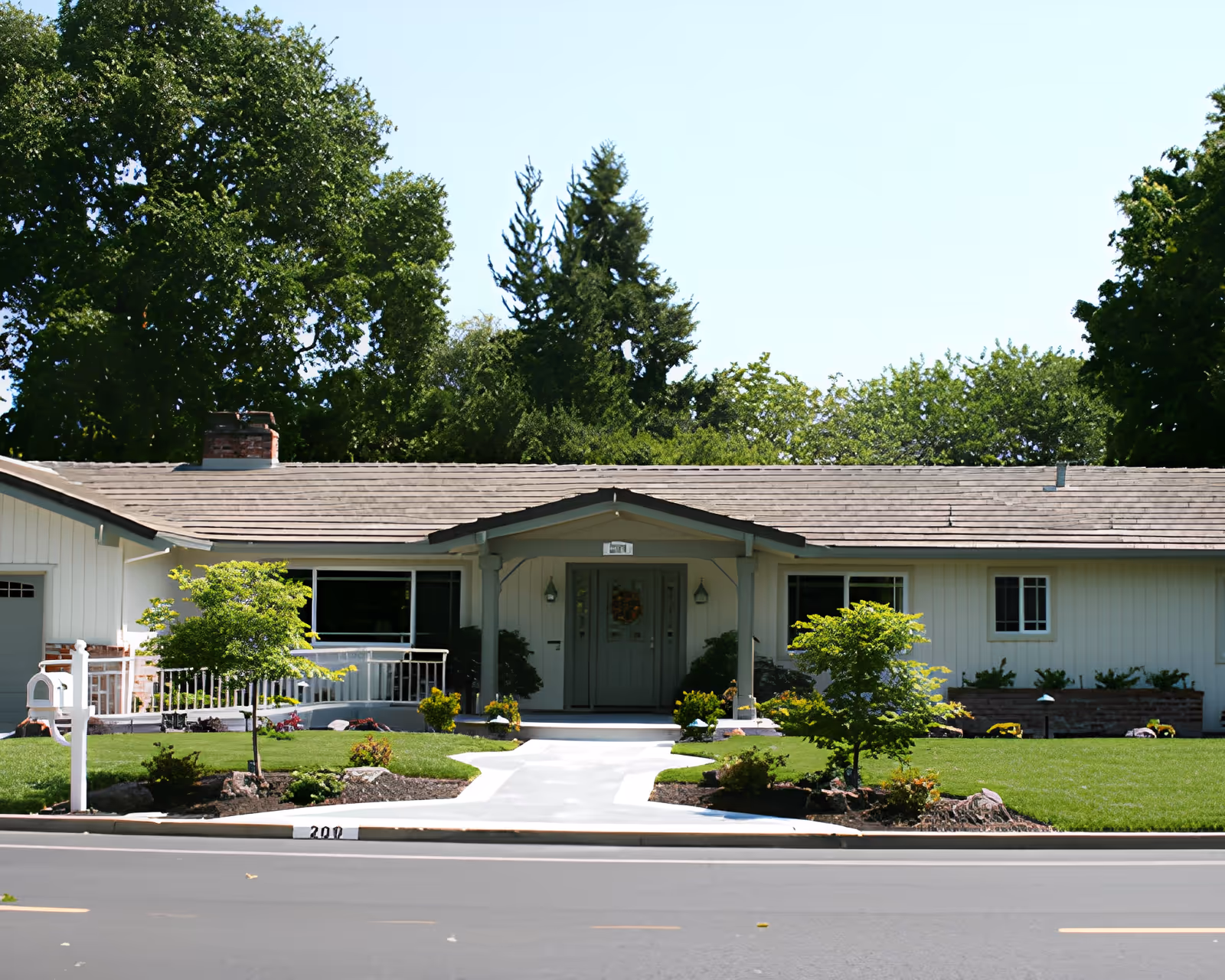 Single-story ranch-style building with a manicured front lawn, walkway, and trees leading to a central entrance.