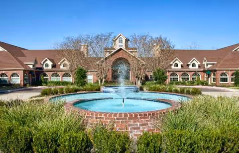 Front view of Village on the Park Friendswood with brick fountain and manicured landscaping.