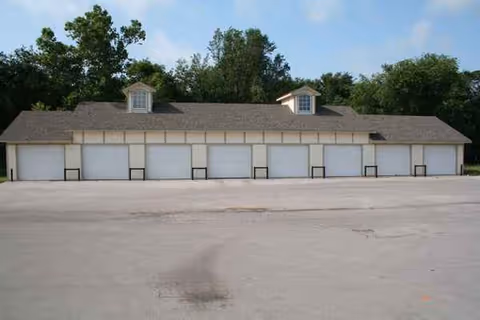 A long single-story building with multiple white garage doors and small dormer windows.