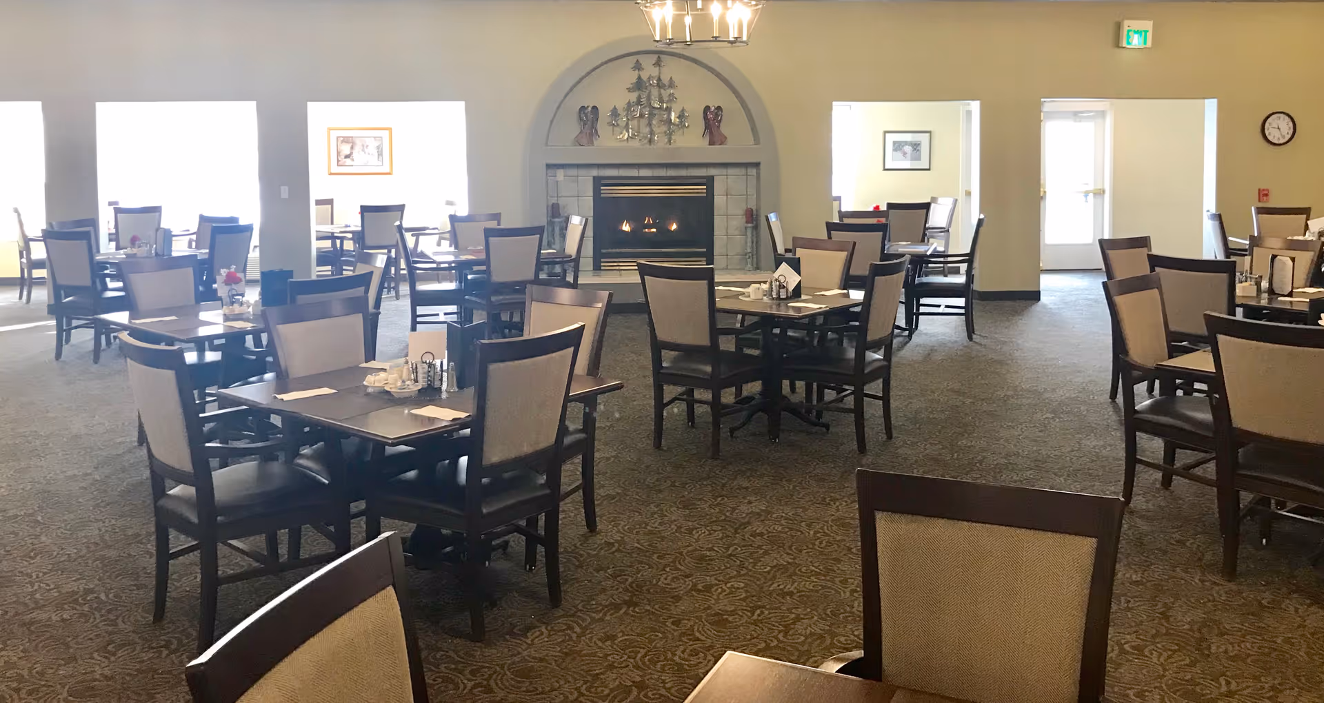 Spacious dining room with multiple tables and chairs arranged around a central fireplace.