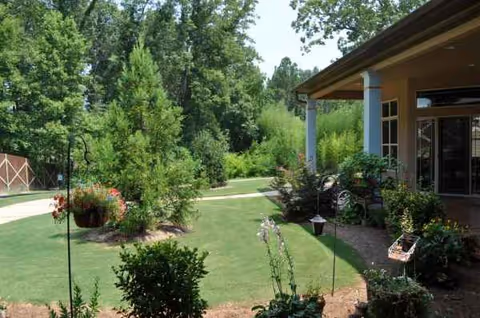 Exterior view of Hamilton Mill Senior Care with lawn, garden, and entrance.