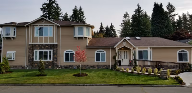 Front view of Sun Village Senior Care exterior with landscaped lawn and trees.
